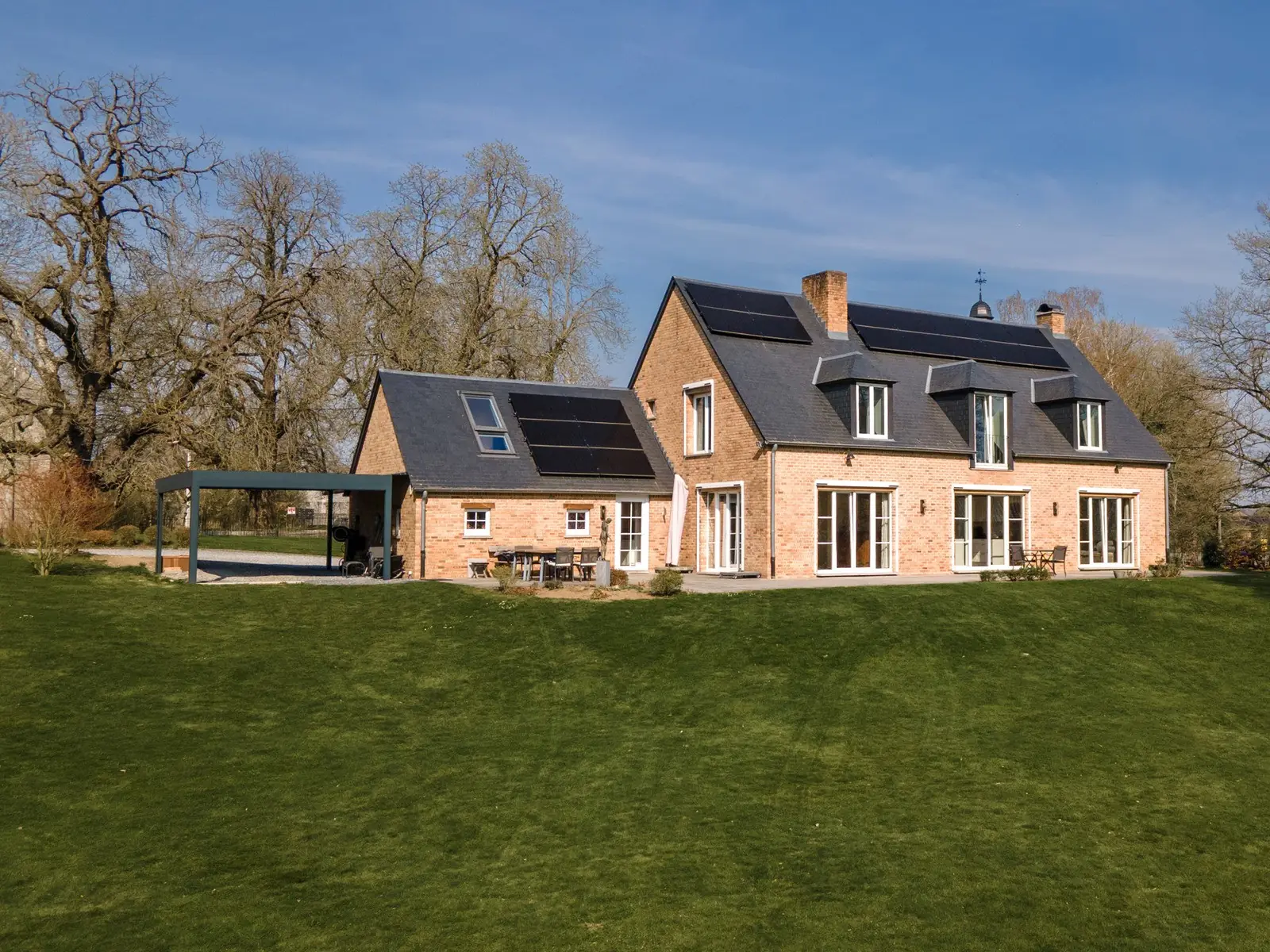 Long corps de logis en brique et toiture d'ardoise à lucarnes, vu depuis sa pelouse, Marchin
