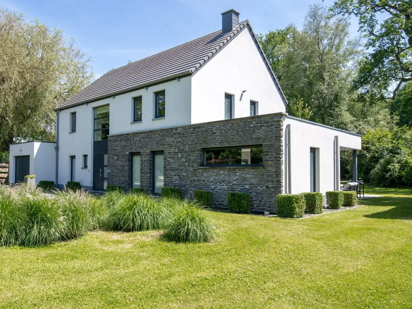 Villa contemporaine : toit plat, baie filante, enduit clair sur soubassement de pierre, Neupré